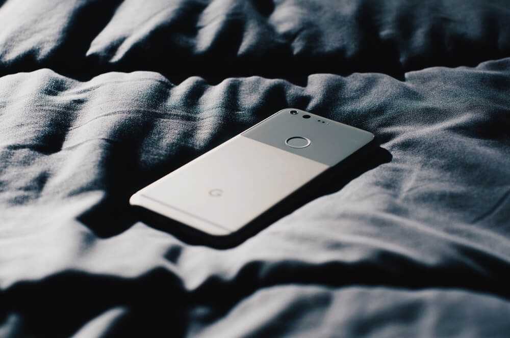 Literally a picture of a phone laying on a bed.